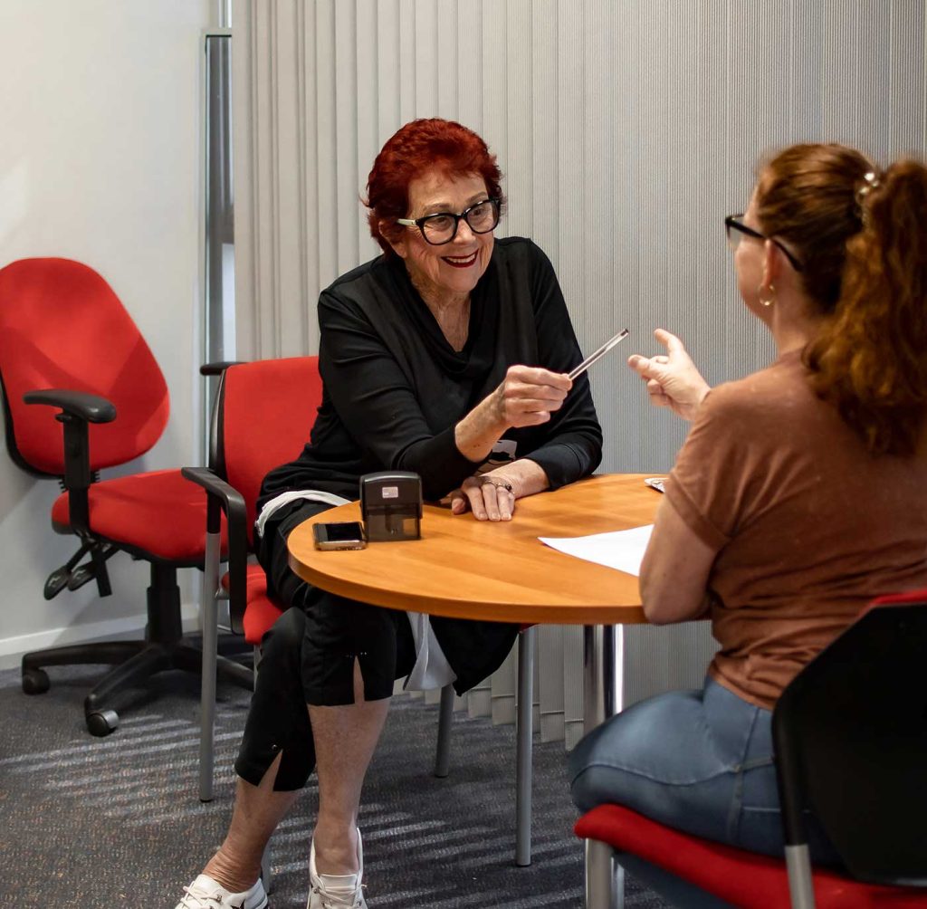 Two woman talking to each other at table